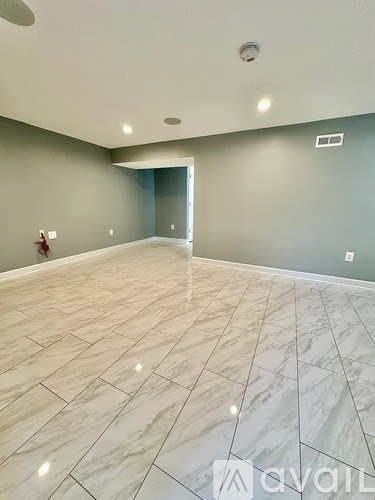 A spacious room with marble tiled flooring and a ceiling light fixture.