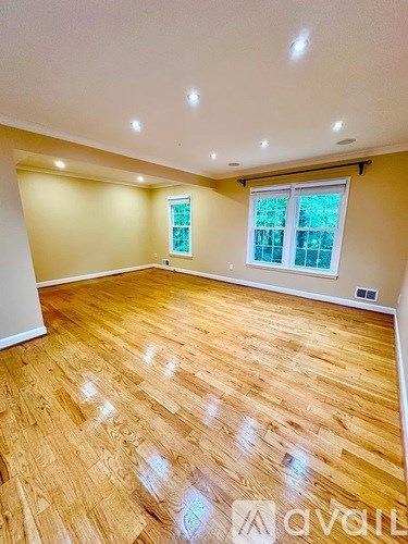 A spacious room with wooden flooring and a window.