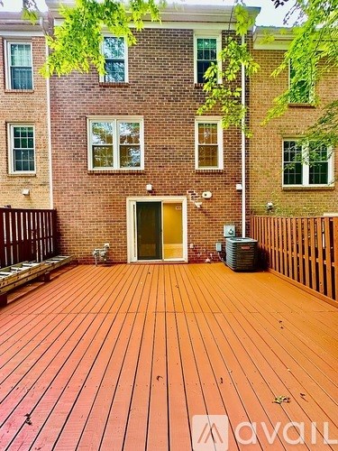 A wooden deck in front of a brick building with a yellow door.