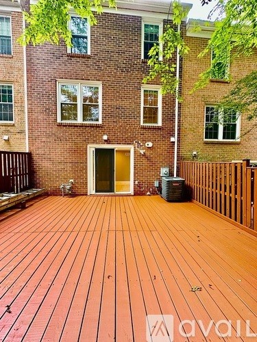 A wooden deck in front of a brick building with a doorway leading to the building.