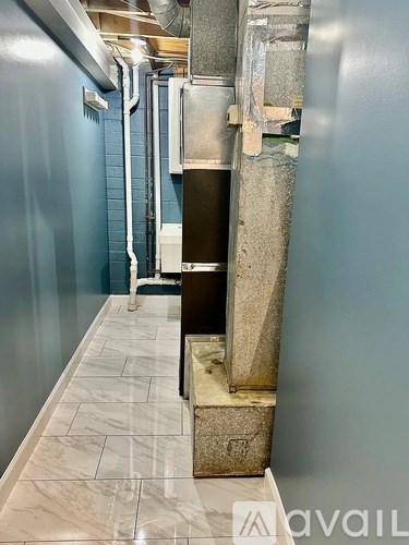 A long hallway with a tiled floor and pipes on the wall.