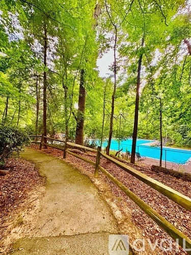 A pathway leads through a wooded area to a pool.