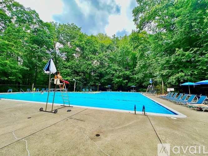 A blue pool surrounded by trees and a lifeguard chair.