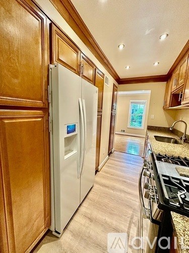 A kitchen with a white fridge and wooden cabinets.