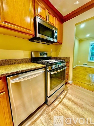 A kitchen with wooden cabinets and a black microwave above the stove.