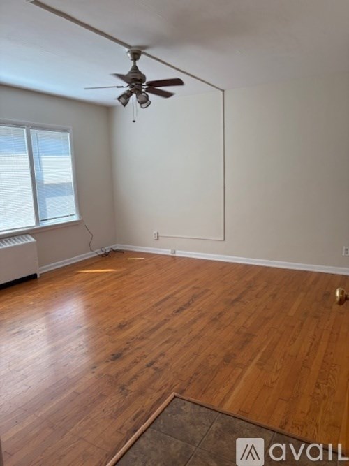 A room with a ceiling fan and wooden flooring.