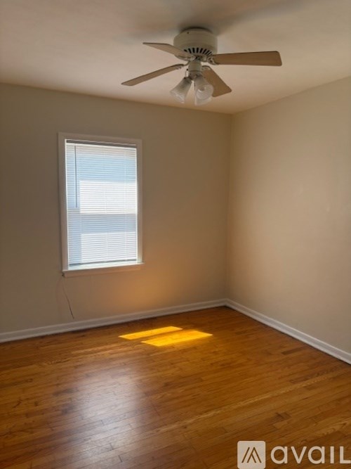A room with a ceiling fan and a window letting in sunlight.