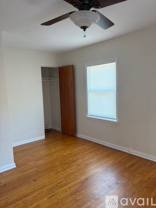 A room with a ceiling fan and wooden flooring.