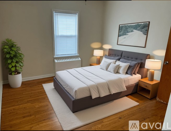 A bedroom with a large bed, a potted plant, and a framed picture on the wall.