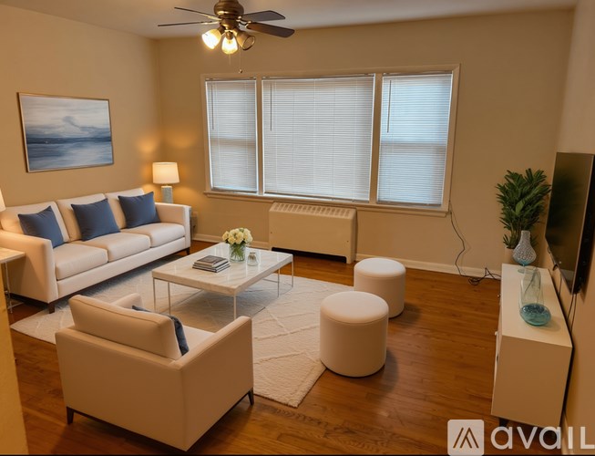 A living room with a white sofa, a white coffee table, and a white ottoman.