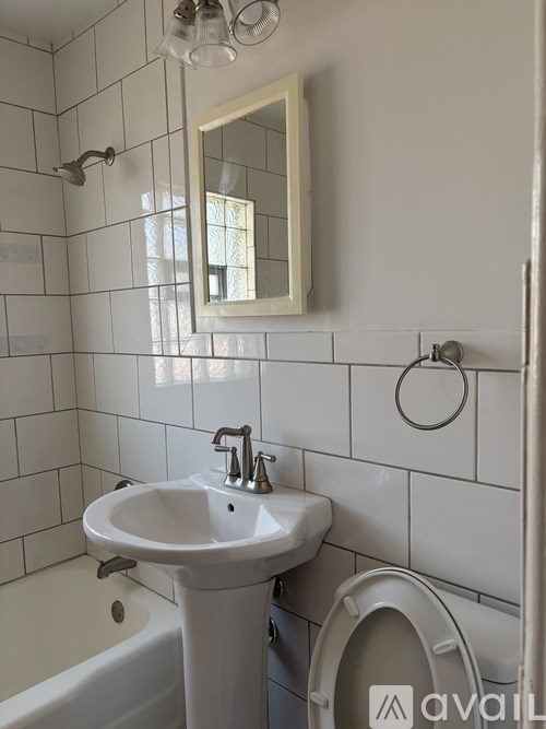 A white bathroom with a sink, mirror, and toilet.