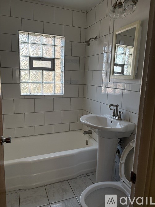 A bathroom with a white sink and a window with a stained glass design.