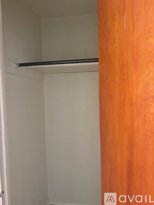 A white closet with a shelf and a wooden door.