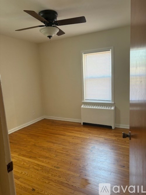 A room with a ceiling fan and a window with blinds.