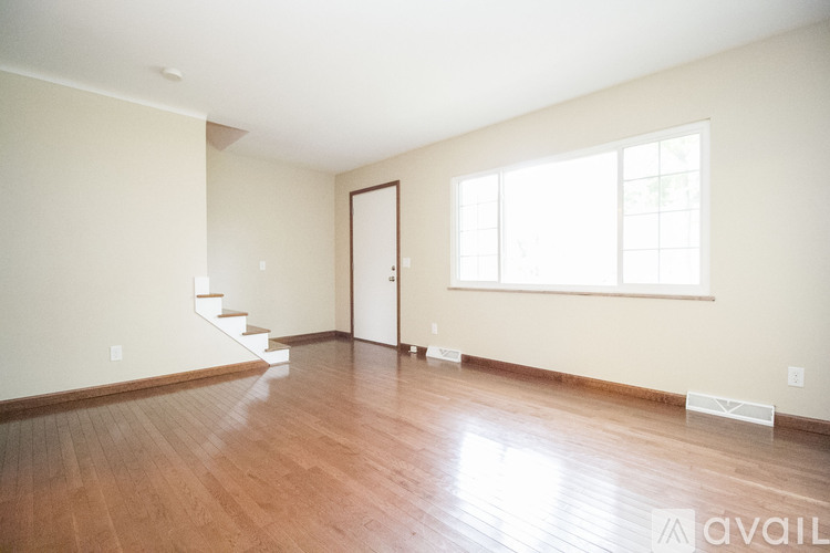 A room with wooden floors and a staircase leading to another room.