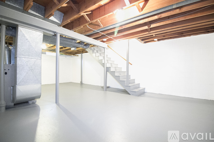 A spacious room with a staircase and a white wall.