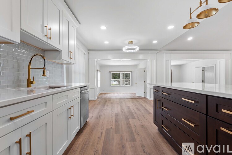 A modern kitchen with white cabinets and dark wood floors.