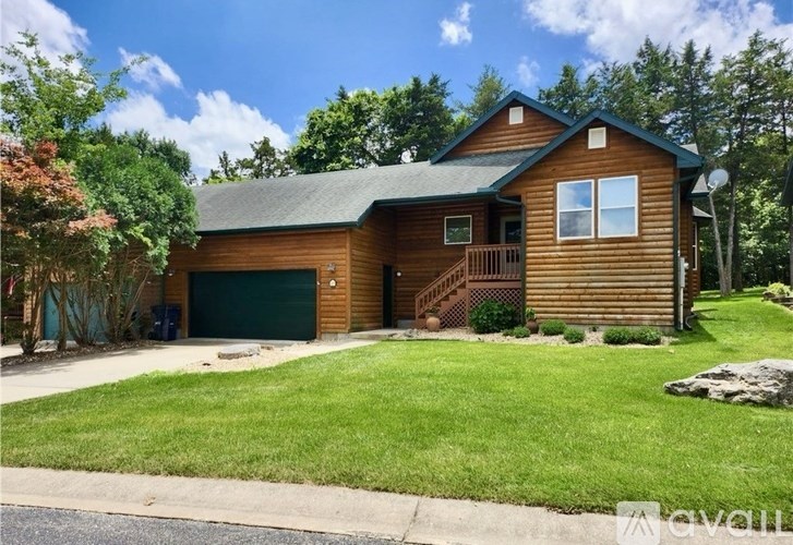 A wooden house with a green garage door and a stone pathway leading to the entrance.