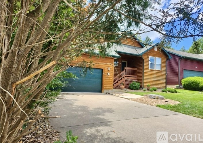 A house with a garage is surrounded by trees and bushes.