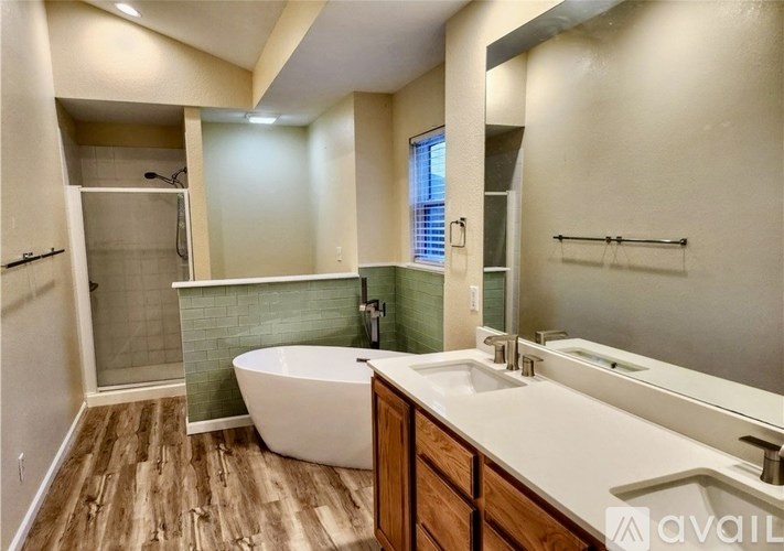 A bathroom with a white tub and wooden floors.
