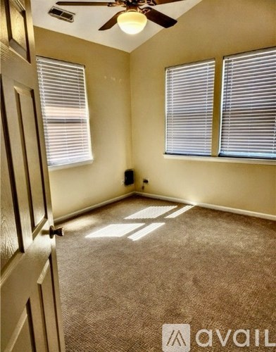 A room with a ceiling fan and two windows.