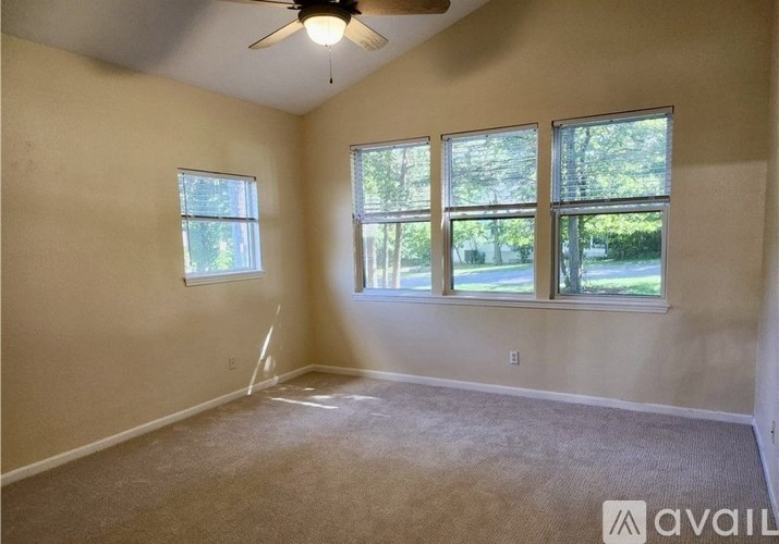A room with a ceiling fan and three windows.