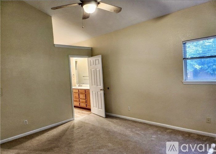 A room with a ceiling fan, a door, and a window.