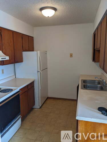 A kitchen with a white refrigerator and brown cabinets.