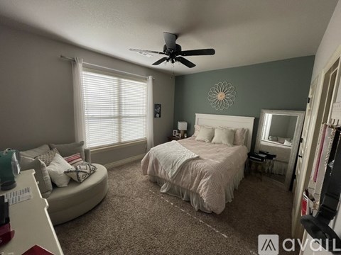 A bedroom with a bed, a fan, and a window with blinds.