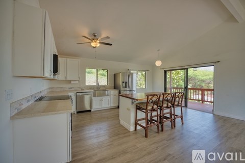 A kitchen with white cabinets and a wooden island with chairs around it.