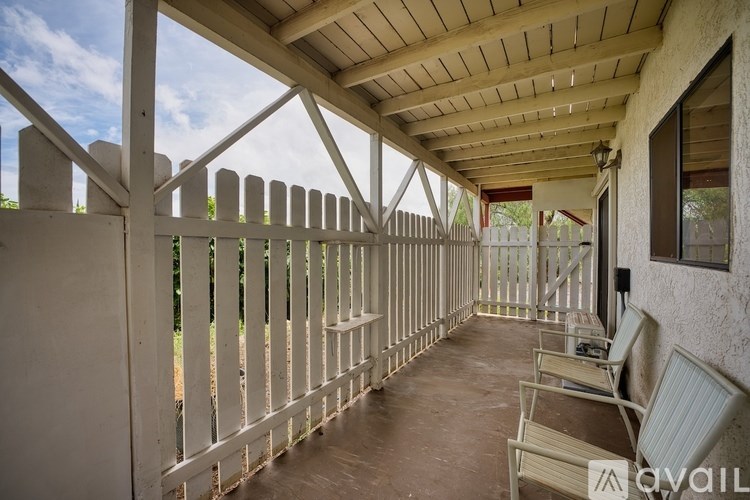 A patio with a white fence and two chairs.