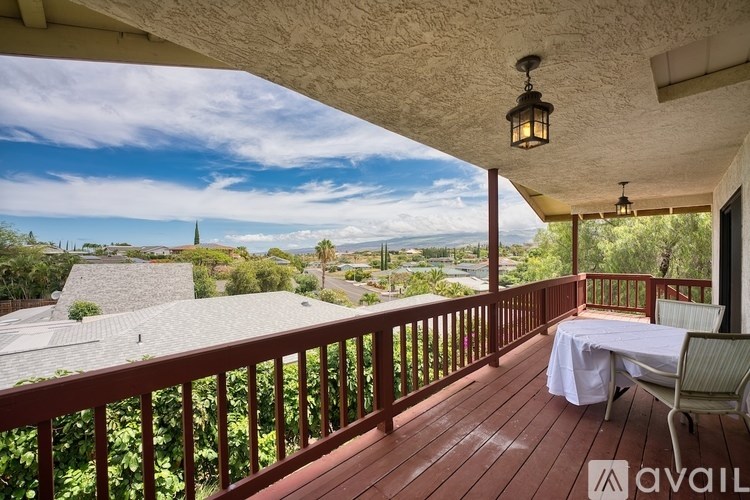 A balcony with a table and chairs overlooking a residential area.