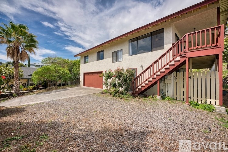 A house with a red staircase and a gravel driveway.