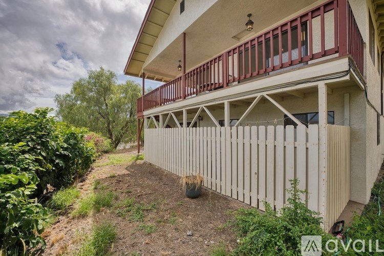 A house with a red balcony and a white fence is for sale.