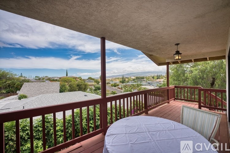 A balcony with a table and chairs overlooking a view of houses and trees.