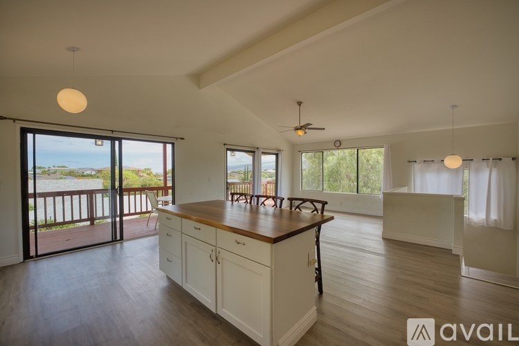 A kitchen with white cabinets and a wooden island is available for rent.