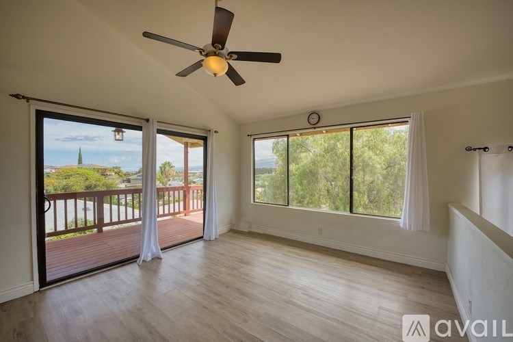 A room with a ceiling fan and sliding glass doors leading to a balcony.