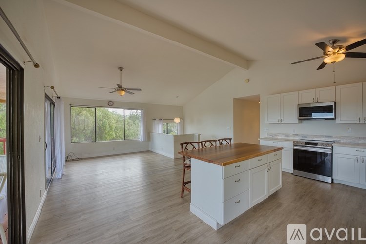 A spacious kitchen and living room with white cabinetry and a wooden island.