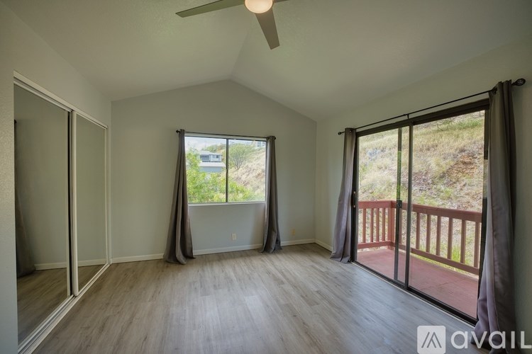 A room with a ceiling fan and sliding glass doors.