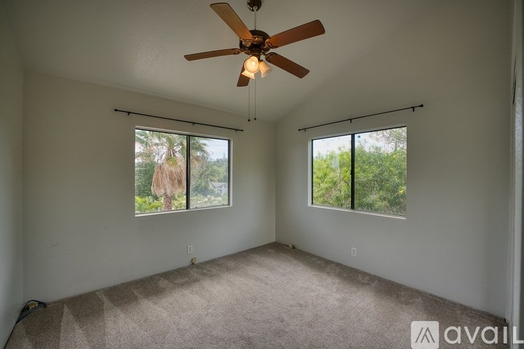A room with a ceiling fan and two windows.