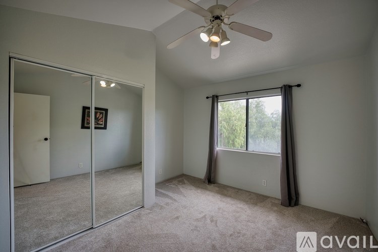 A room with a ceiling fan and a sliding glass door leading to a balcony.