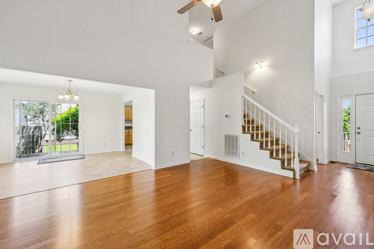 A spacious room with wooden floors and a staircase.