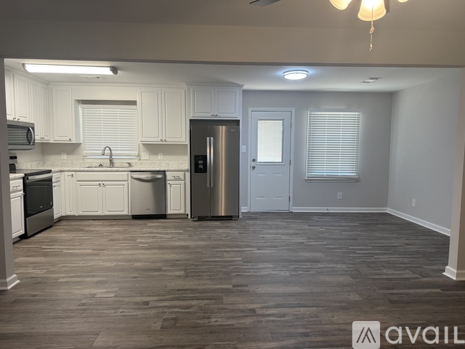 A kitchen with white cabinets and a wooden floor.