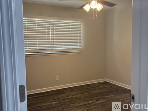A room with wooden floors and a window with blinds.