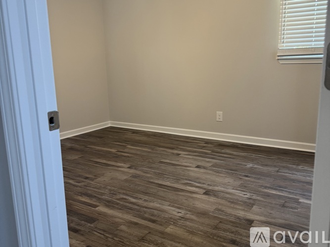A room with wooden flooring and a door on the left.