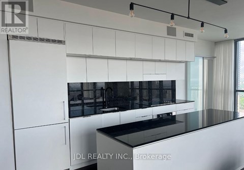 A modern kitchen with white cabinets and black countertops.