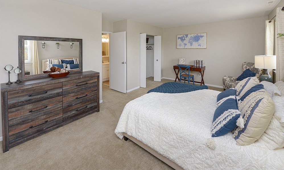 a bedroom with a bed and a dresser and a mirror