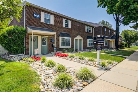 the front of a brick building with a sidewalk and landscaped front yard