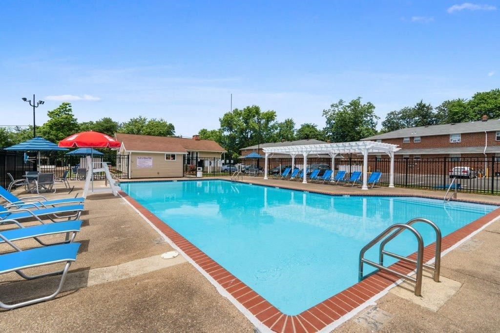 a swimming pool with chairs and umbrellas next to a building
