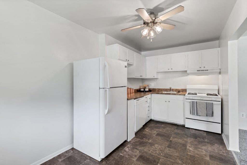 a kitchen with white appliances and a ceiling fan